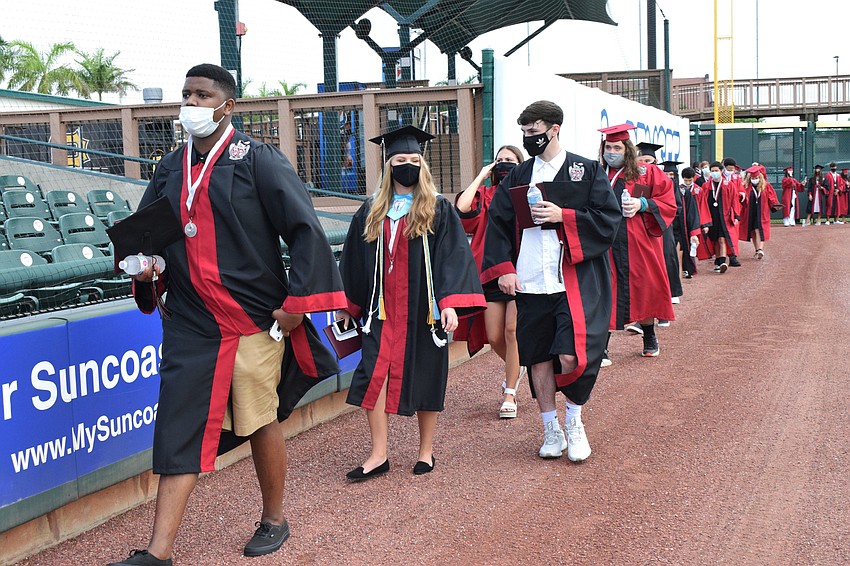 Graduates walk around the baseball field.