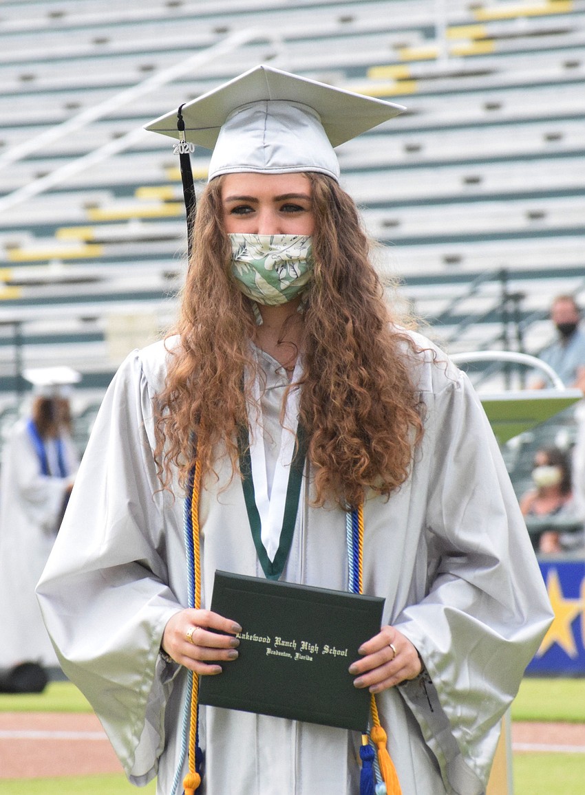 Emily Brandt proudly holds her diploma while walking across the field. 