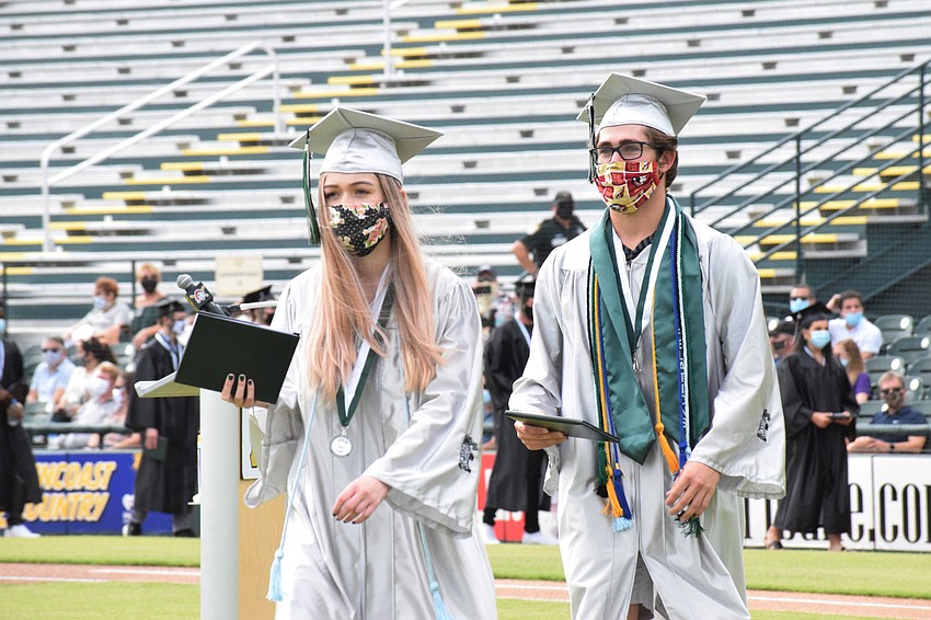 Sophie Walker and Zack Weston make their way across the field with their diplomas.