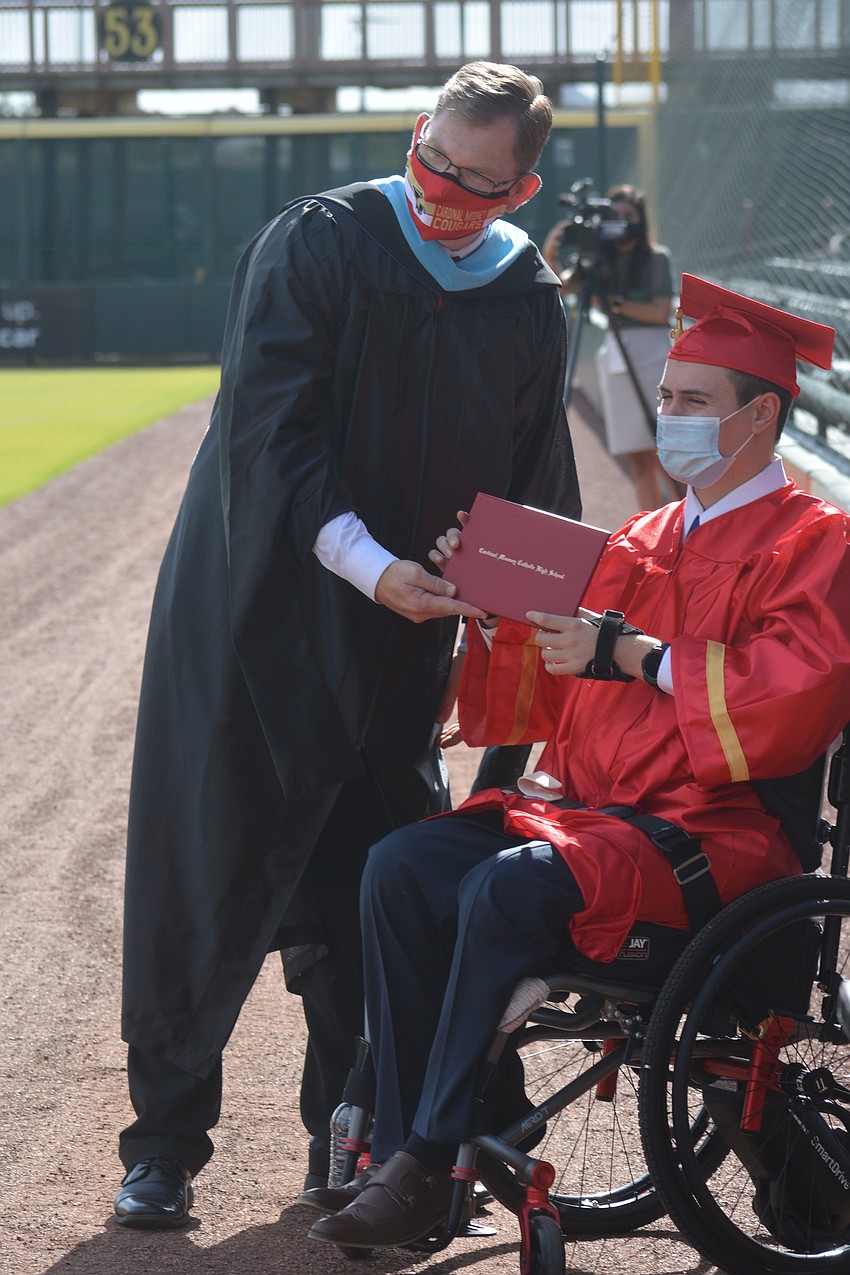 Michael Bavaro receives his diploma from Mooney principal Ben Hopper. Bavaro, who injured multiple vertebrae in a boating accident in March, received a large ovation from the crowd.