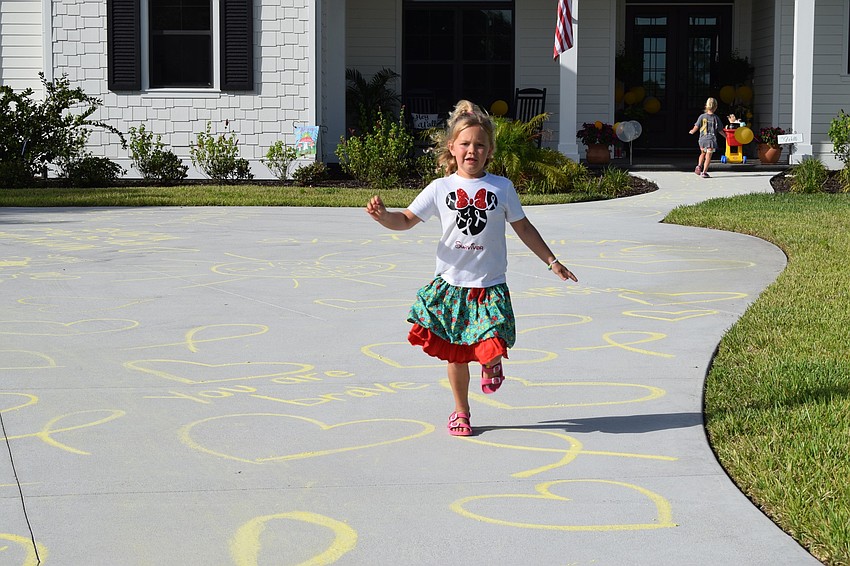 Charlotte Wells runs down her driveway, which is covered in positive messages written in yellow chalk to celebrate her last day of chemotherapy.