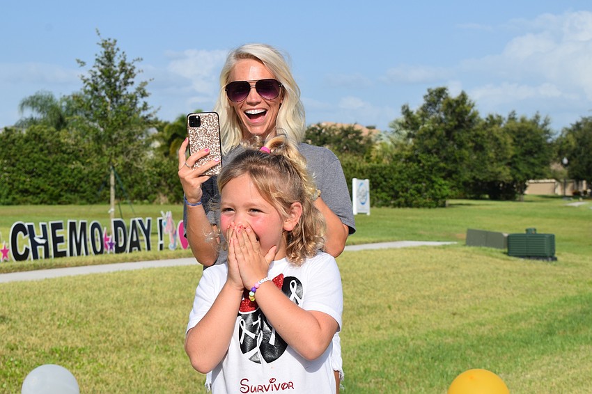 Rachel Wells takes video as her daughter Charlotte Wells is in shock from the surprise appearance of emergency medical service vehicles and firetrucks at her parade to celebrate her final day of chemotherapy.