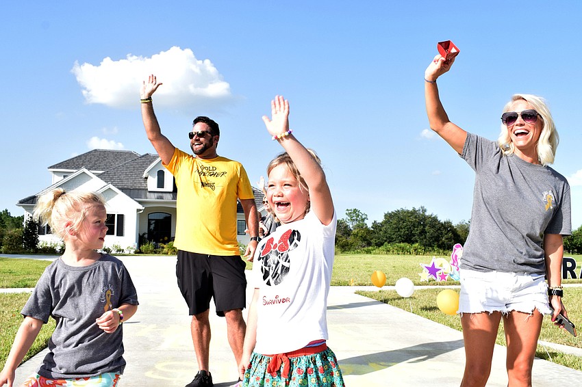 Savannah, Matt, Charlotte and Rachel Wells cheer as family and friends start to pass their house in a parade.