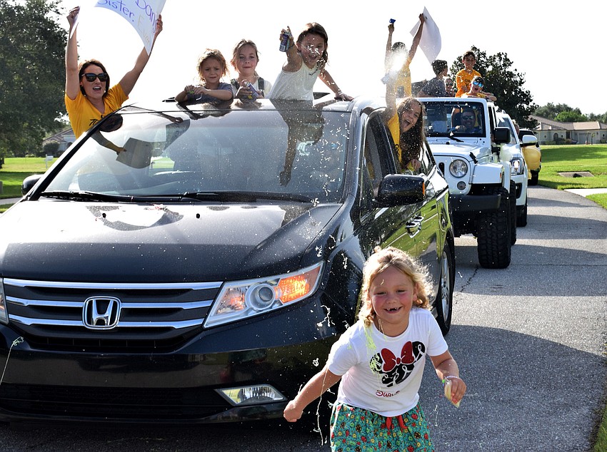 Charlotte Wells runs as family and friends try to spray her with silly string from their cars.