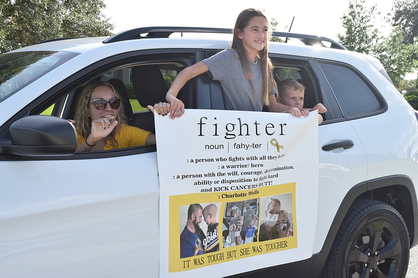 Danielle, Emma and Chase Avery give Charlotte Wells a sign they made her calling Wells a fighter for battling cancer the past two years.