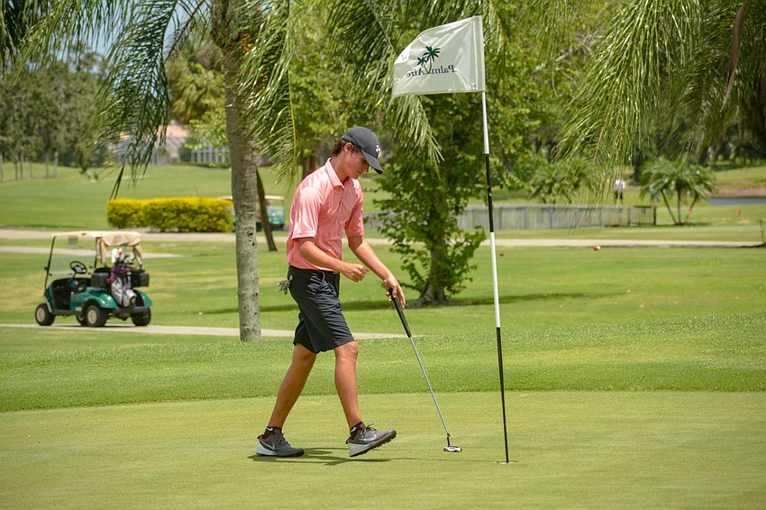 Logan Veith, who attends Braden River High, picks up his ball after sinking a putt to win his first match.