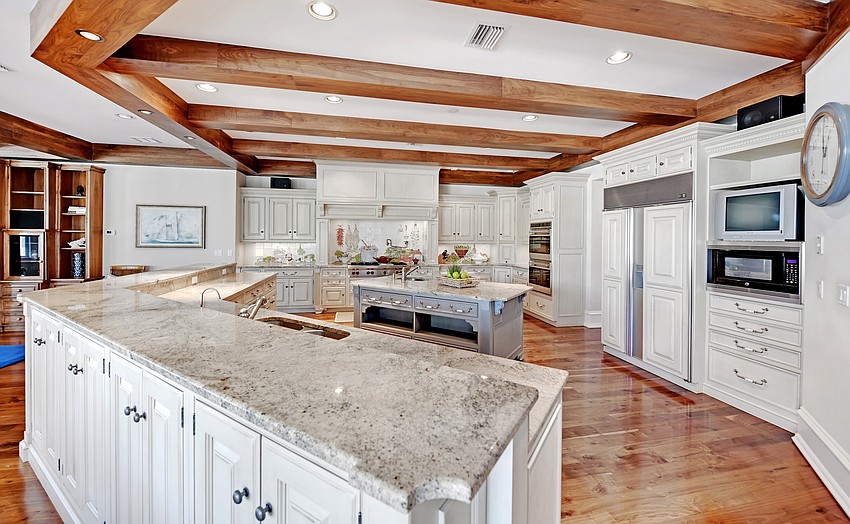 The kitchen features a Wolf six-burner gas cooktop, double convection ovens, warming drawers, Sub-Zero refrigeration, walk-in pantry, large center island and counter seating.