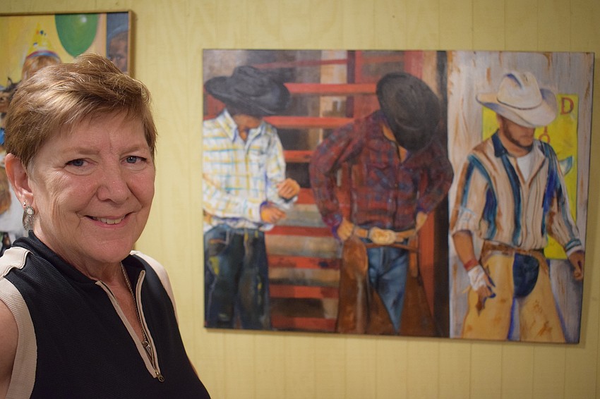 Deb Herbert stands in front of a oil painting she did at MJ Ranch in Myakka City.