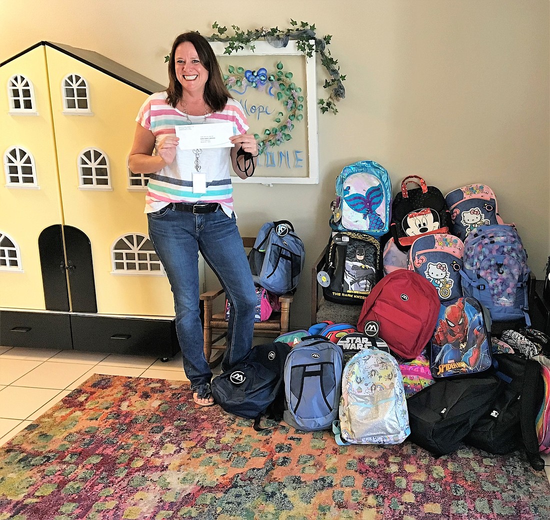 Stacy McKee, development director of HOPE Family Services, accepts backpacks for the children at the shelter and a donation check from the Lakewood Ranch Women&#39;s Club. Courtesy photo.