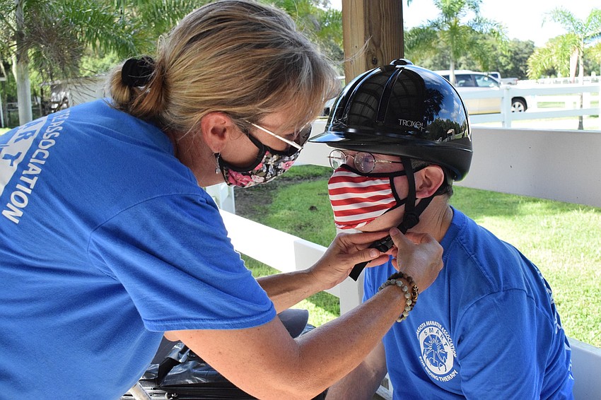 Samantha Toomey, an equine manager at Sarasota-Manatee Association for Riding Therapy, helps Dan Mohl put his riding helment on before his lesson.
