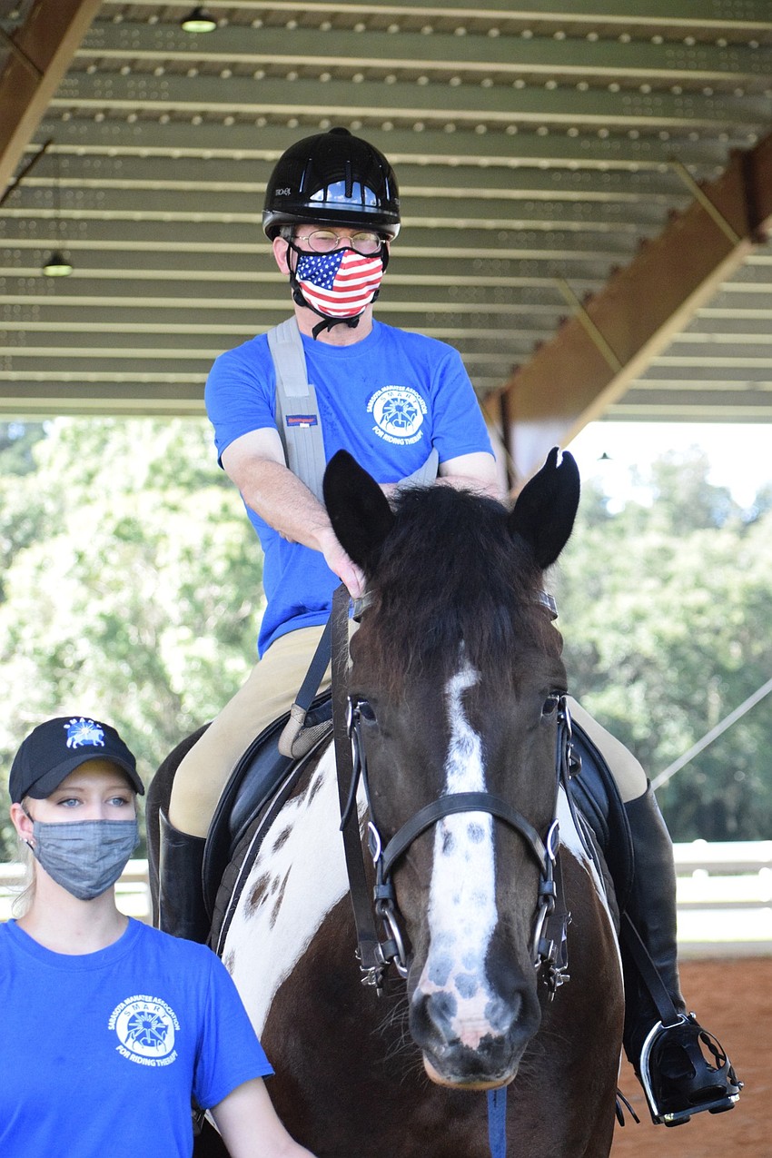 Megan Jones, a volunteer for the Sarasota-Manatee Association for Riding Therapy, helps guide Gallagher as Dan Mohl rides.