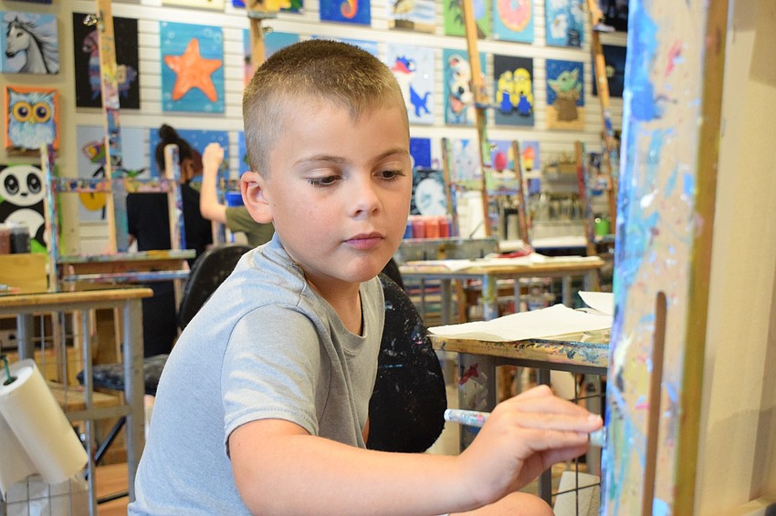 Cooper Colon, a second grader at Robert E. Willis Elementary School, focuses on his sundae painting. He painted one scoop red, blue and yellow, which is inspired by the Superman ice cream at Big Olaf Creamery.