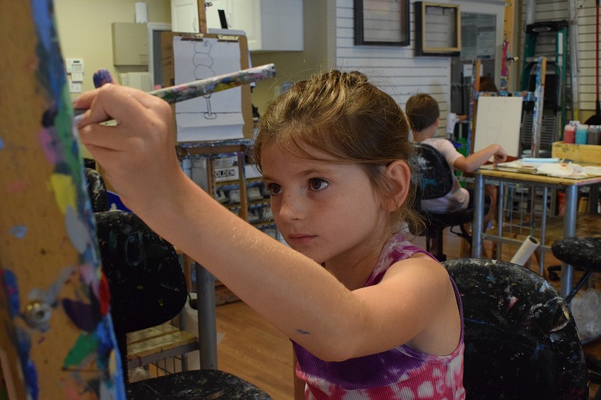Adriana Buchanan, a third grader at Providence Community School, focuses on painting the background of her canvas pink.