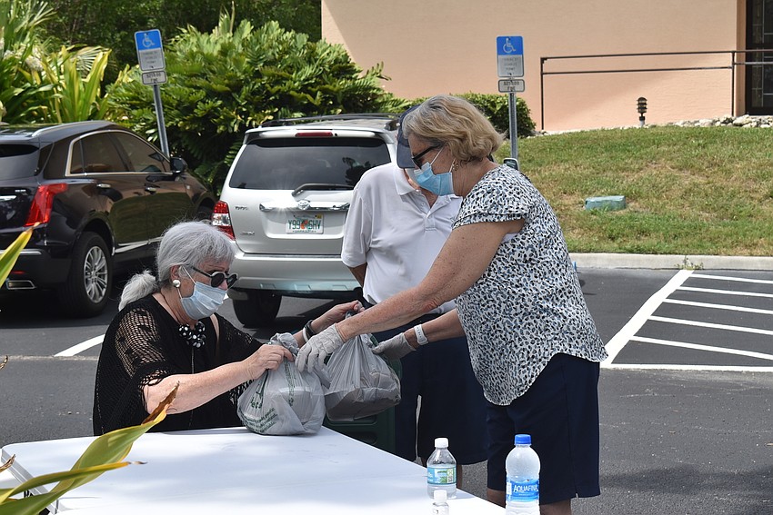 Sylvia Pastor hands the allotted two meals to Sandra Packard.