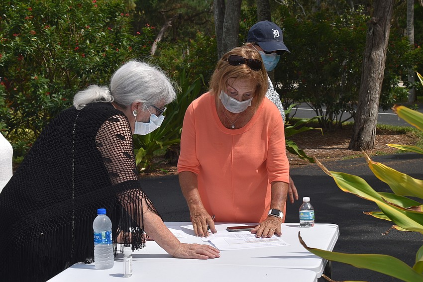 Sylvia Pastor and Marion Levine check the table of meal pick-ups.