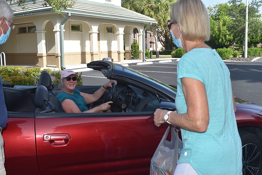 Sally Rauch picks up a bag from Carol Erker's car and says hello at a distance.