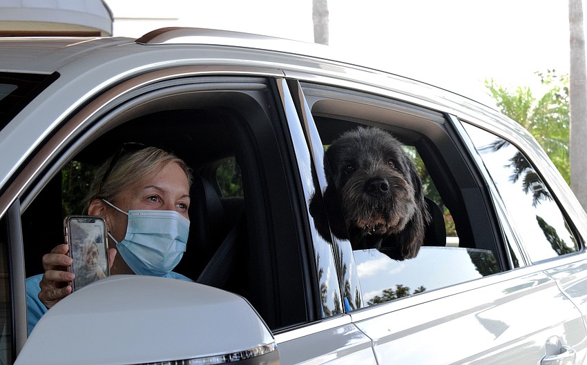 The Lake Club's Pamela Benson holds up her phone so her husband, Brian Benson, can talk to the Hermann family through a video call.