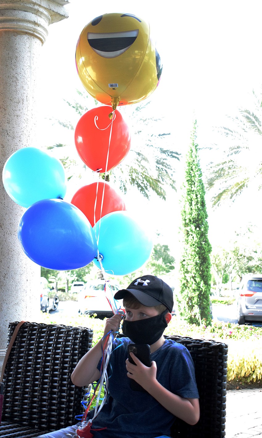The Lake Club's Grayson Hermann holds onto balloons for his brother, Weston Hermann.