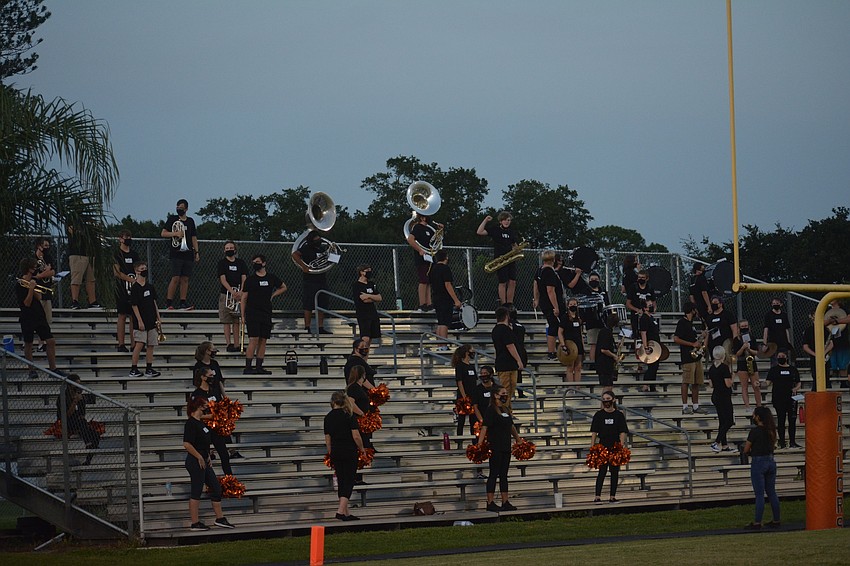 The Sarasota High band and cheerleaders perform from the bleachers while socially distanced.