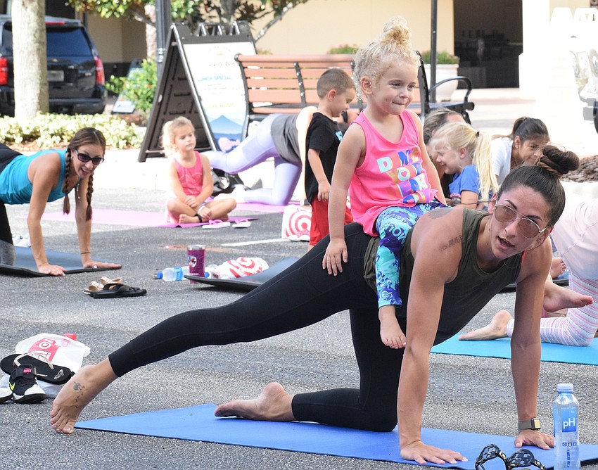 Lakewood Ranch's Dallyn Doehr, who is 4 years old, sits on top of her mother, Alexx Doehr while she works out.