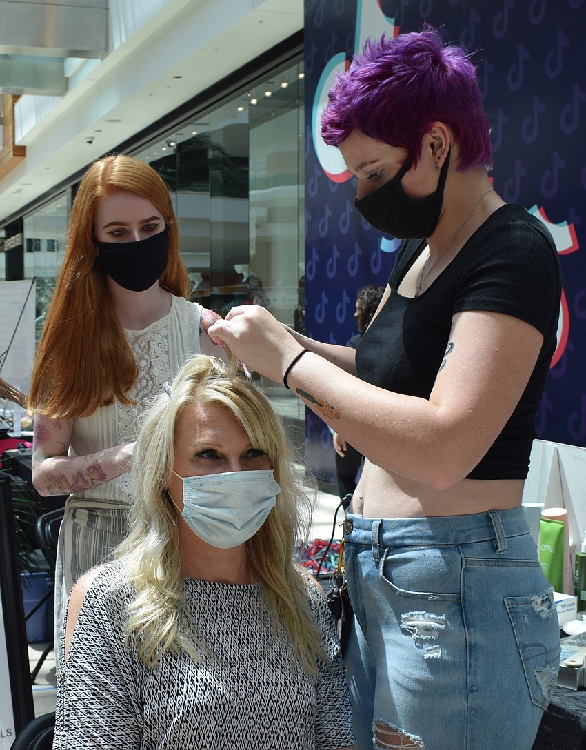Dominique Dunnigan with Angela's Pure Salon and Spa watches as Palmetto's Penny Boston gets a blue streak put in her hair by Taylor Peacock, who works at the salon and spa.