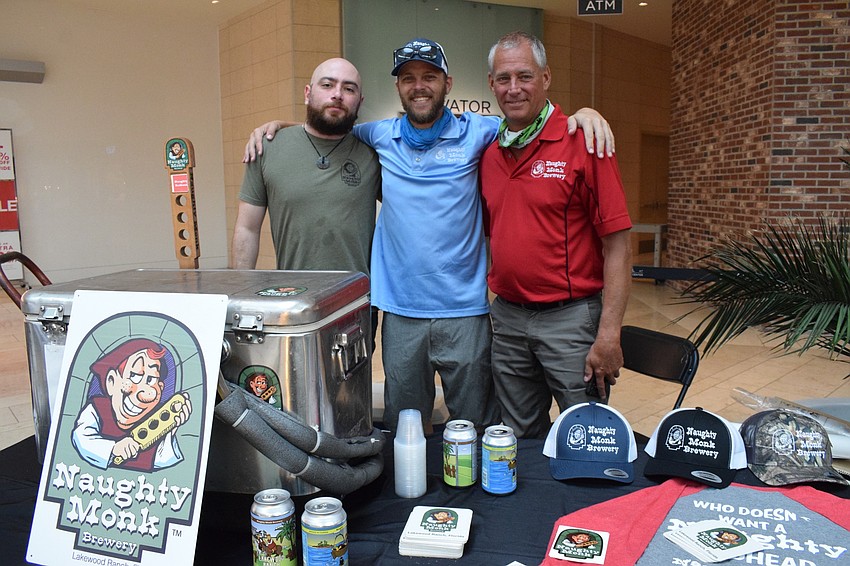 Damien Hickle, head brewer at Naughty Monk Brewery, passes out samples to expo participants with Anthony and Joe Eibler.
