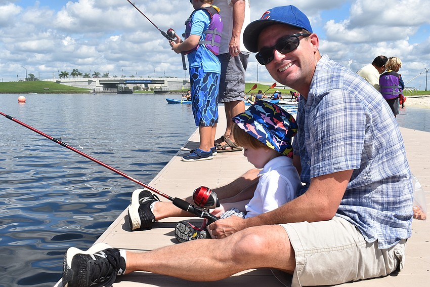 Ted Phillips (right) helps his son, Benji Phillips, to fish. Ted, who is visiting from Alexandria, Virginia, said he was excited to get some sun and time near the water.