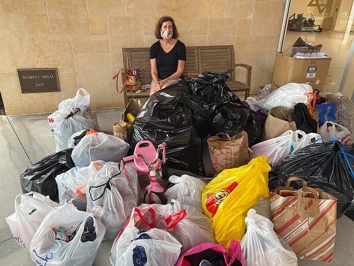 Judy Polivy sits with the many donations collected at Temple Sinai.