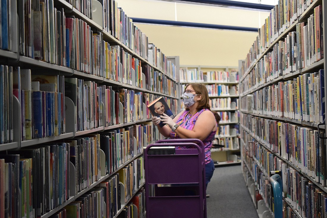 Jill Eisenbeis, a library assistant, gathers materials for curbside orders. Braden River Library will start providing curbside service again Oct. 1. File photo.