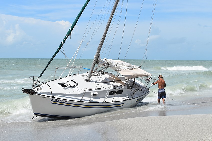 Mark Sternal examines his sailboat washed ashore near 4239 Gulf of Mexico Drive in Longboat Key, Florida.