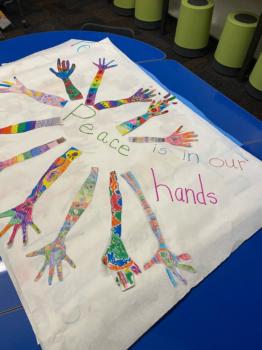 Second graders trace their arms and decorate them for what peace means to them. The arms are put on a banner to say, 