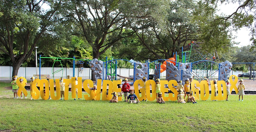 Students smile for a photo next to a 