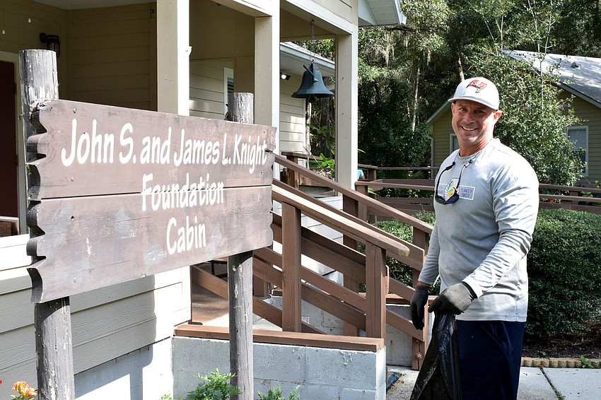 Ryan Riley with Servis First Bank helps clear the front of the John S. and James L. Knight Foundation Cabin after trimming some bushes.