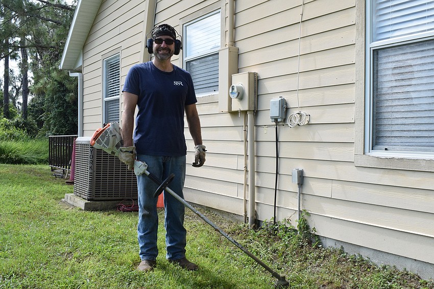 Michael Hassell with Smith Seckman Reid uses a weed trimmer to clean up the areas around the cabins.