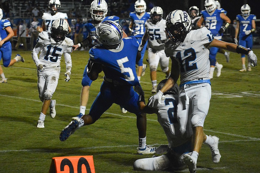 Nolan Lewellen (22) and Michael Wyatt Carlton (12) chase down Canterbury running back Barry White (5).