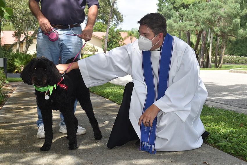 Ed Upshaw hangs onto energetic Reba as Father Dave Marshall gives her her blessing.