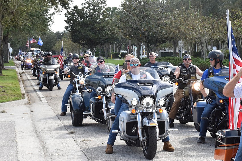 Dozens of people on motorcycles drive through the parade to celebrate Roger Quisenberry's 100th birthday.