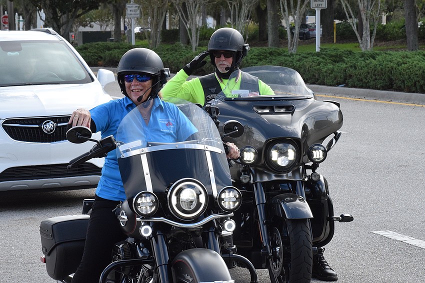 Terry Dansbury, a member of the Lakewood Ranch Elks Lodge, rides alongside her husband, Matthew Dansbury, as he salutes Roger Quisenberry, a veteran celebrating his 100th birthday.