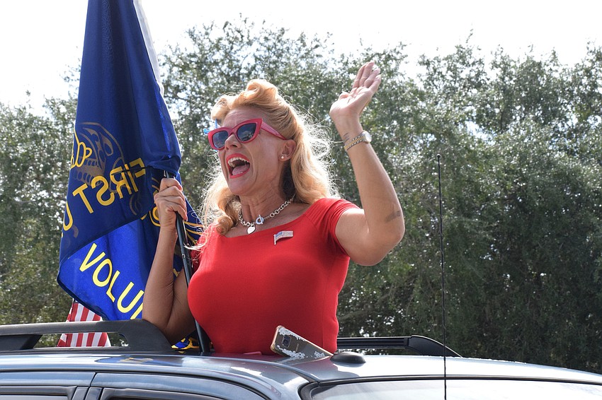 Dawn Peters with the Honor Flight of West Central Florida waves and wishes Roger Quisenberry, a veteran, a happy 100th birthday. 