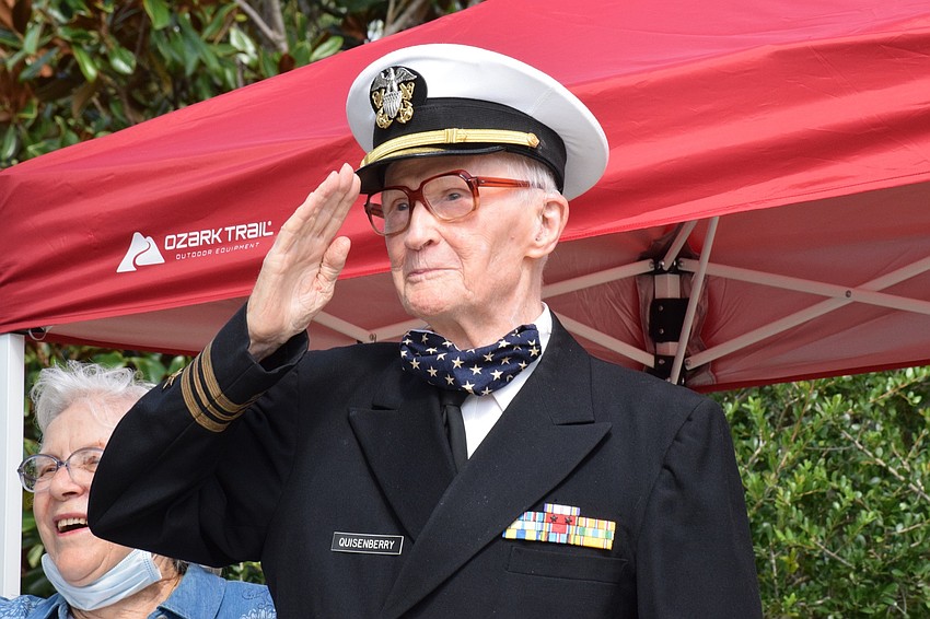 Roger Quisenberry, a World War II veteran, salutes the various veteran groups and community members as they pass by during a parade to celebrate his 100th birthday.