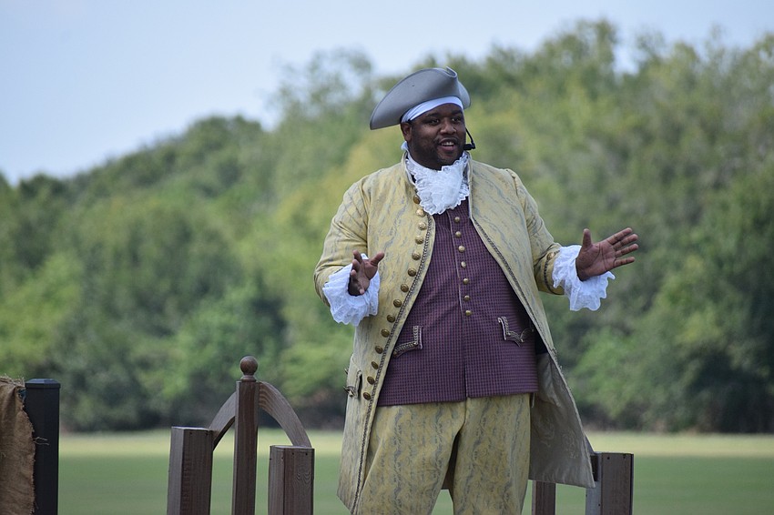 Mr. Bantus Van Tassel (Eldred Brown) addresses the audience.