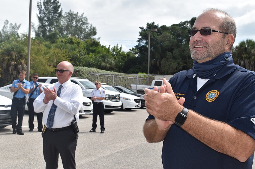 Detective Lt. Robert Bourque (left) and Town Manager Tom Harmer (right) applauded Pete Cumming as he drove off in retirement.