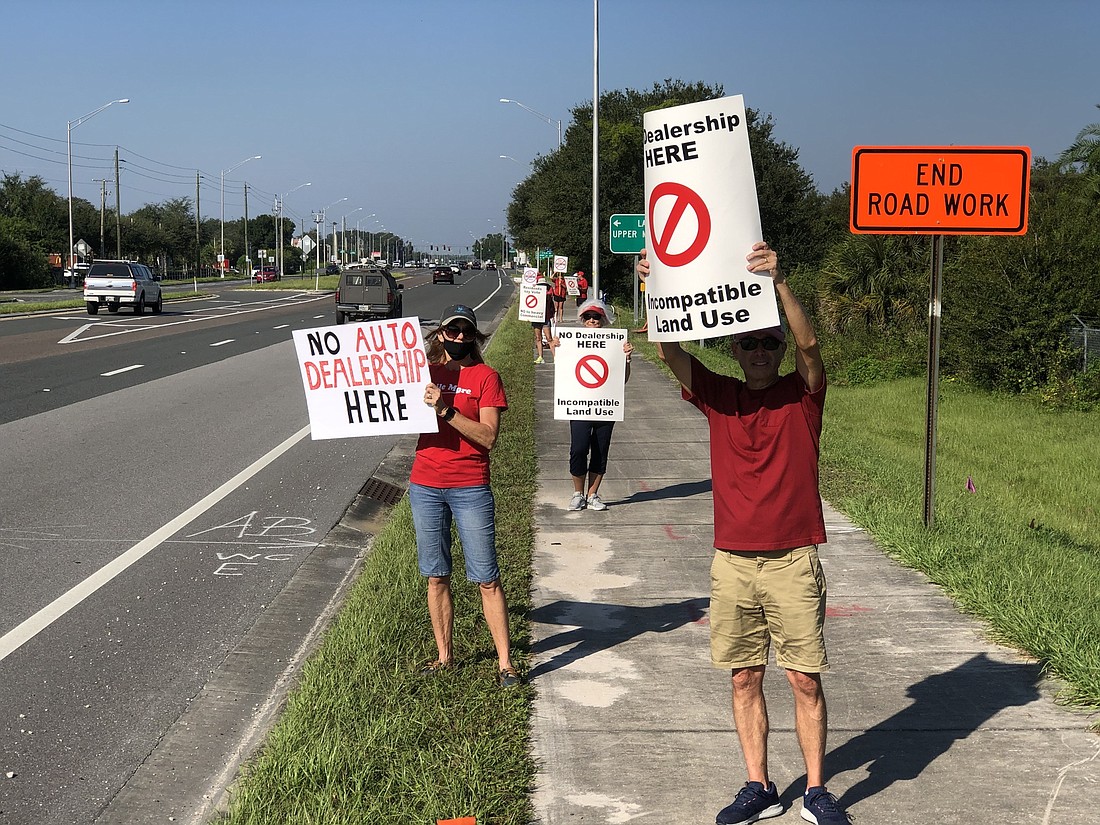 Opposed residents who live near the site of the proposed dealership protest in front of the site Oct. 17 on State Road 64. Some residents plan to file an appeal after a county commission vote paved the way for a car dealership.