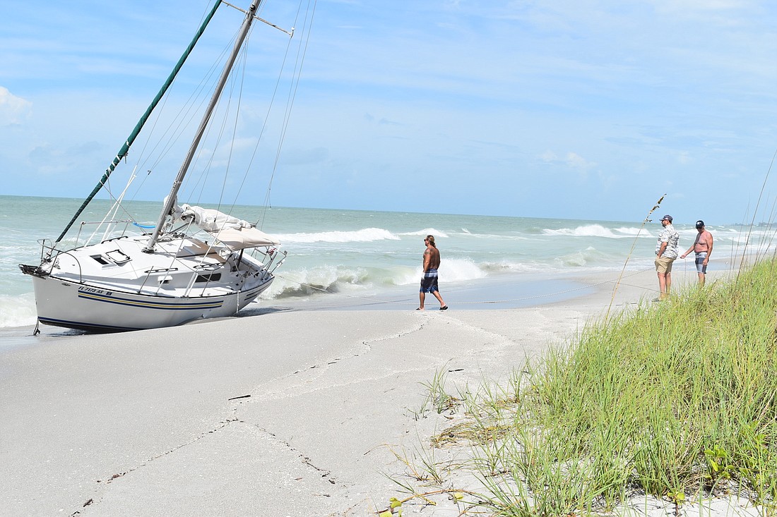 Mark Sternal (left) examines his sailboat washed ashore near 4239 Gulf of Mexico Drive in Longboat Key, Florida.