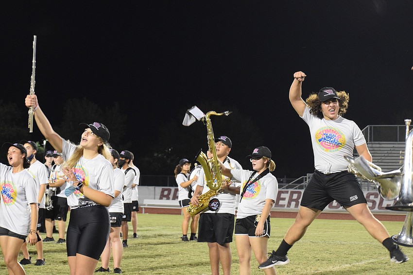 Members of the Marching Band of Pirates jump and cheer while performing the school's fight song.