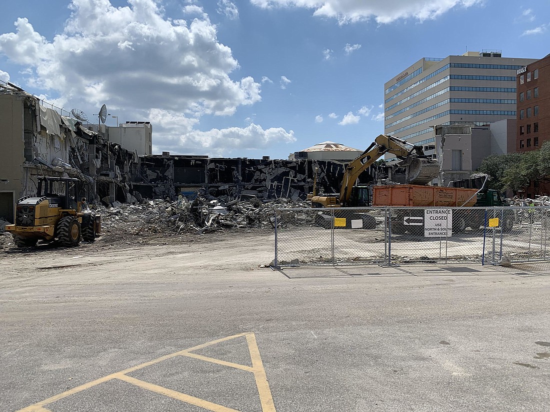 Construction crews knock down a portion of the Main Plaza shopping center to clear space for a residential-focused project still awaiting city approval.