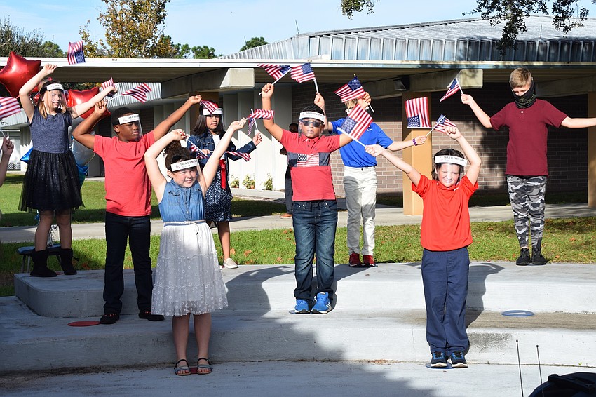 Fourth graders wave their flags along to the song.