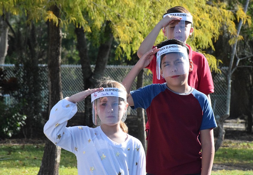 Fourth graders Fayth McMullan (front), Alexander Izquierdo and Dawson Normandin salute to veterans during a song.