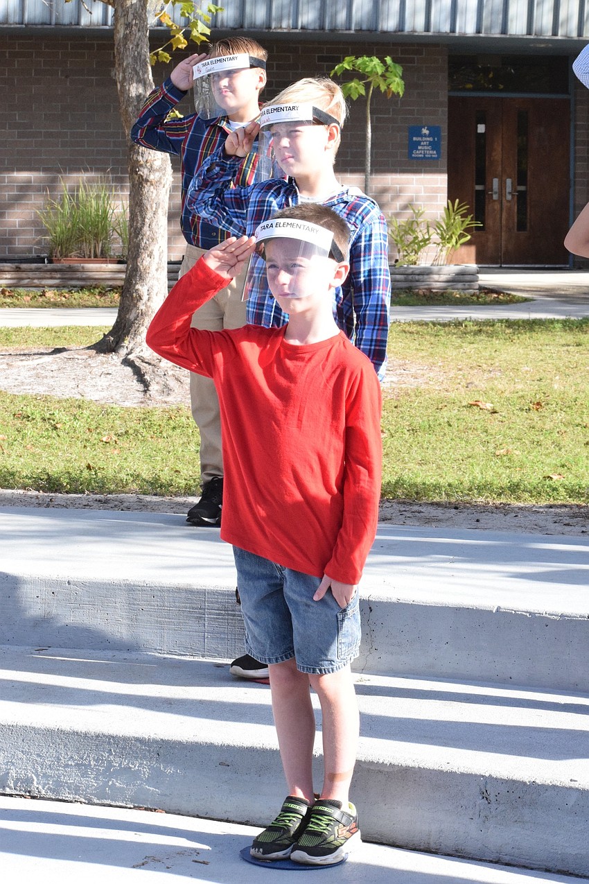 Fourth graders Tyson Norris (front), Isaiah Cerquizzi and Gavin Grosso salute in unison to honor veterans.