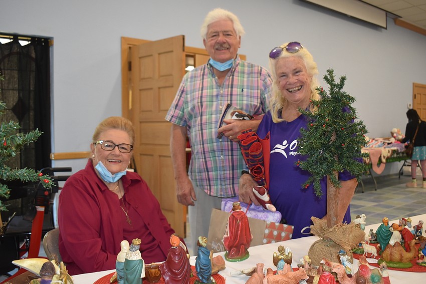 Andy Youngs sits at the table stocked with nativity scenes as Chuck and Ursula Dimler stop to chat.